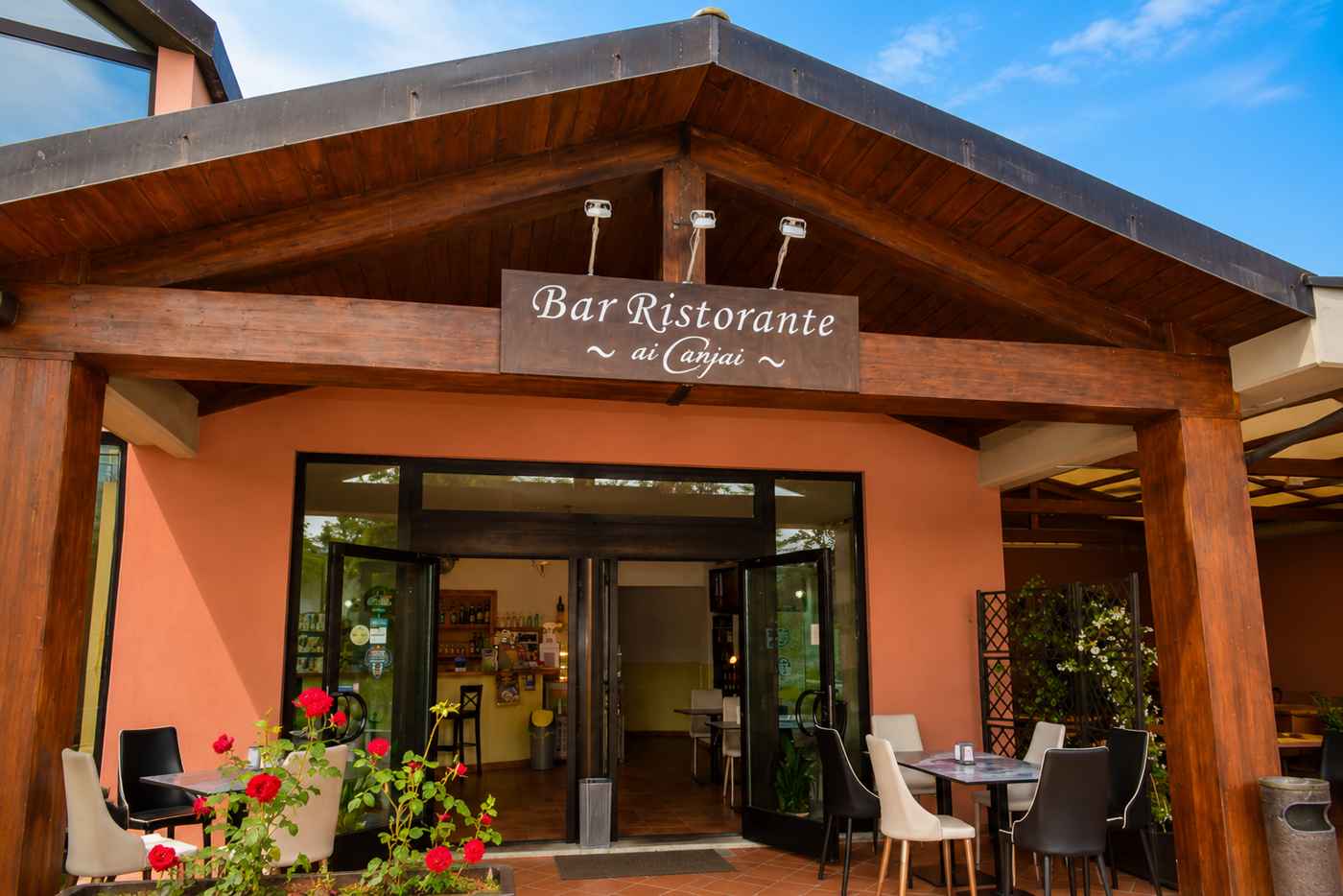 Ingresso del Bar Ristorante Ai Canipai con tavoli all'aperto e rose